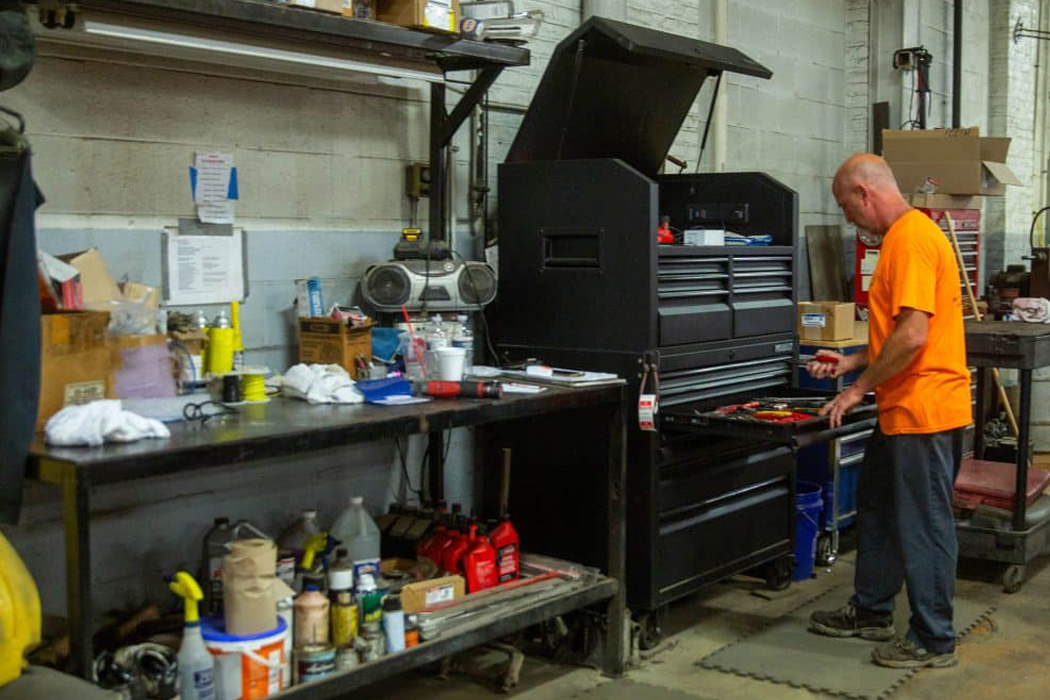 Man in a neon orange shirt looking through a tall black tool box