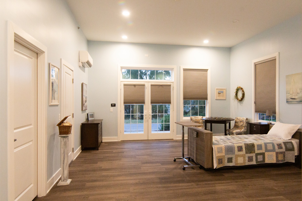 Bedroom with blue walls, a few windows, a bed with a checkered pattern, chairs, and a dresser.
