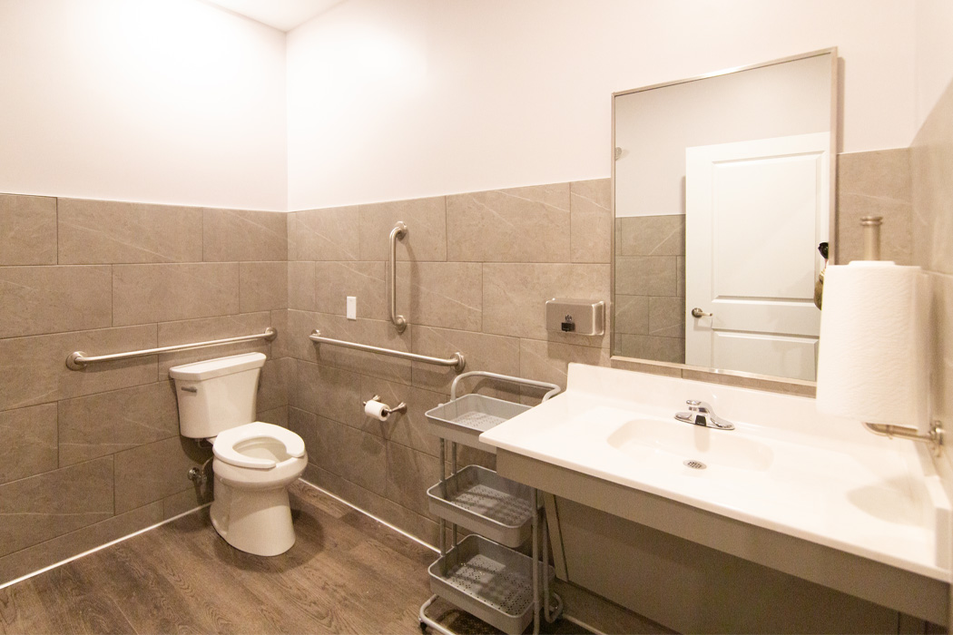 Handicap accessible bathroom with beige floors and wall tiles