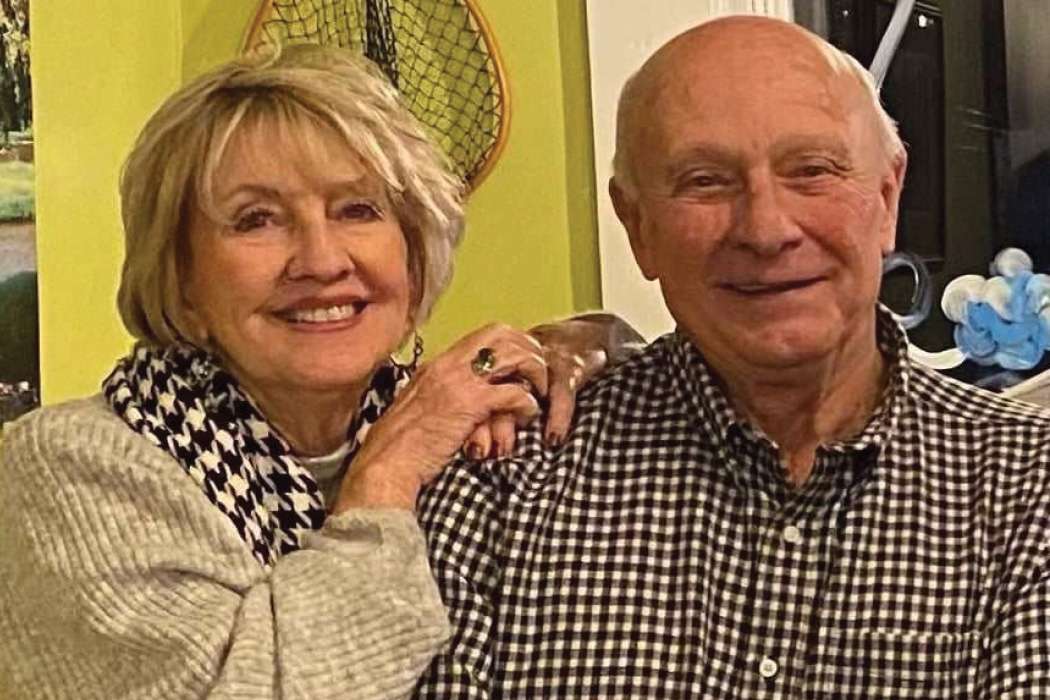 Picture of a woman in a grey sweater and a man in a plaid button up shirt in front of a lime green wall.