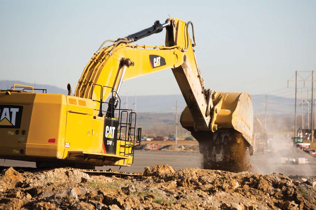 Yellow excavator digging dirt with utility poles in the background