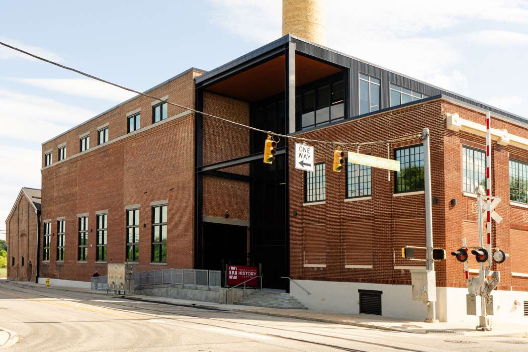A renovated brick building stands at a street corner, featuring a modern glass addition.