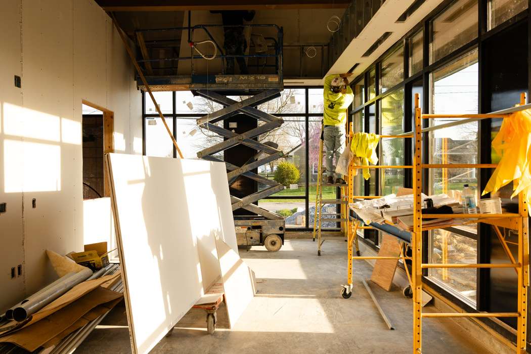 Sunlight streams into a building under construction, illuminating scaffolding, tools, and building materials.