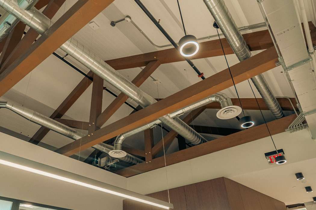 Exposed wooden beams and industrial ductwork crisscross a high ceiling.