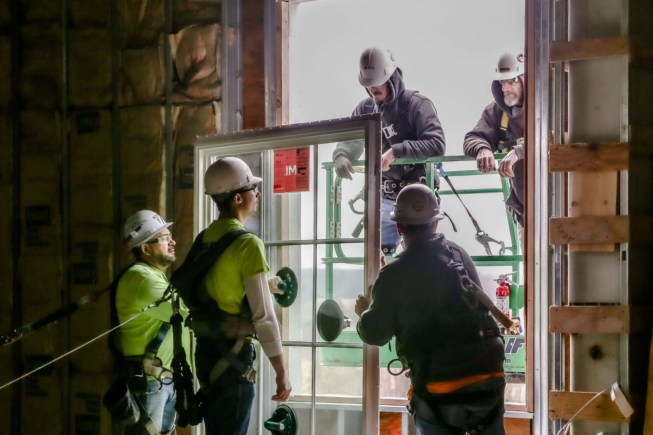 Construction workers install a large window.