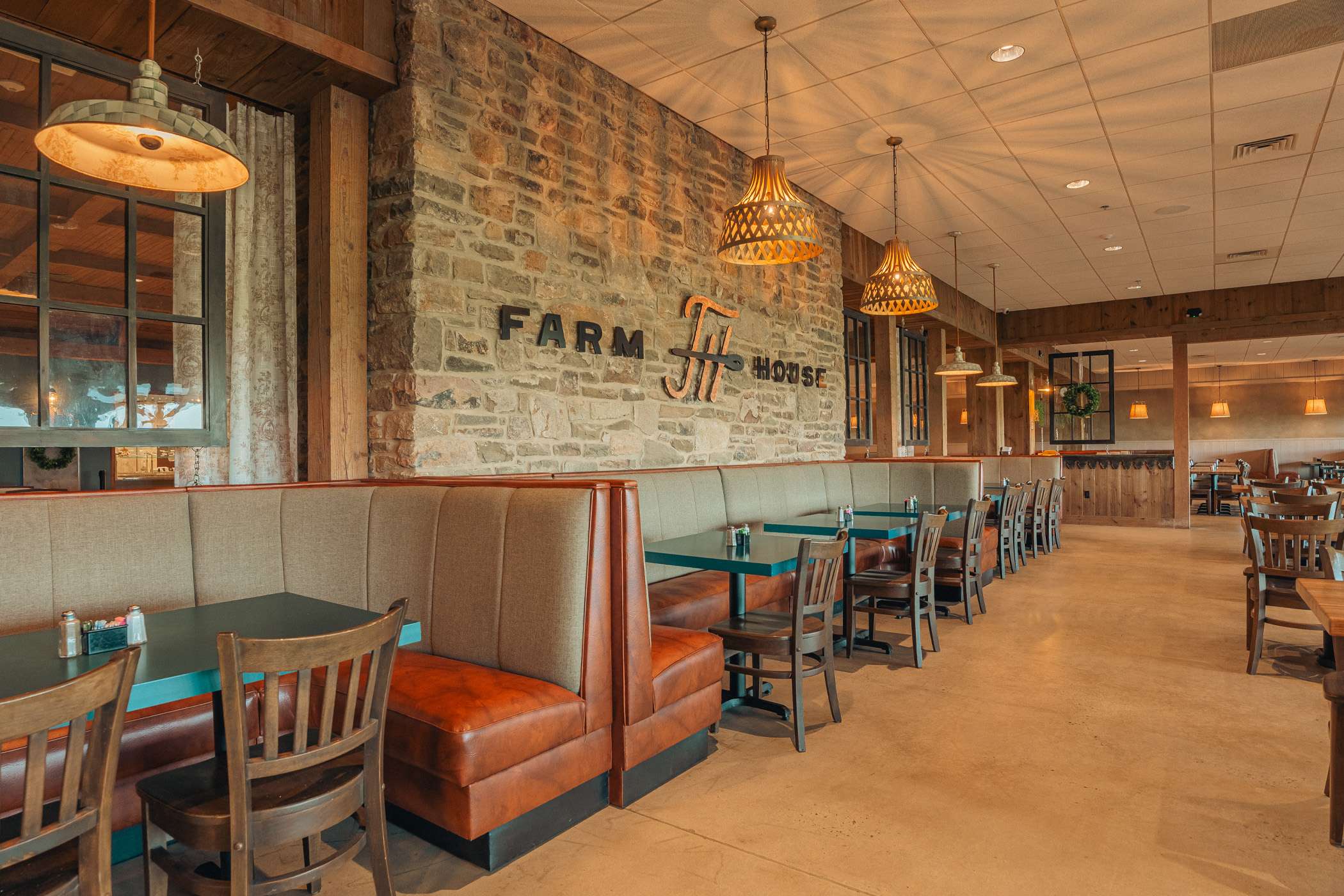 A restaurant interior with booths and tables, featuring a rustic brick wall and pendant lighting.