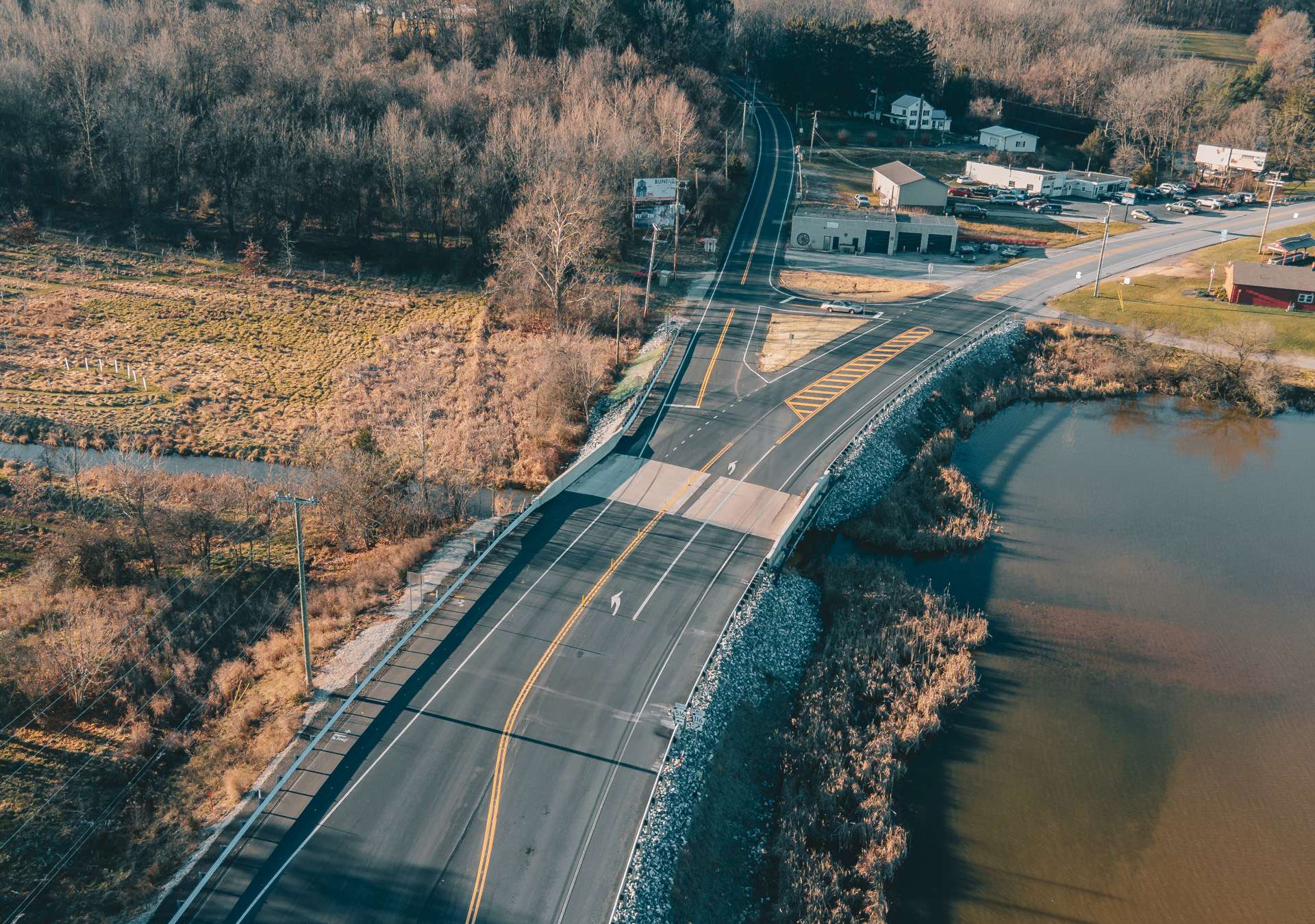 golden-hammer-award-road-hero Aerial view of a highway spanning over a lake with a town and trees in the distance.
