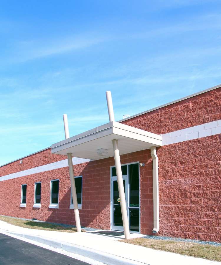 An entrance with a canopy stands out from a brick building under a blue sky.