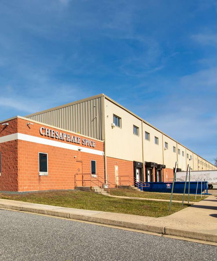 An orange and tan building with "Chesapeake Spice" on the side sits under a blue sky.