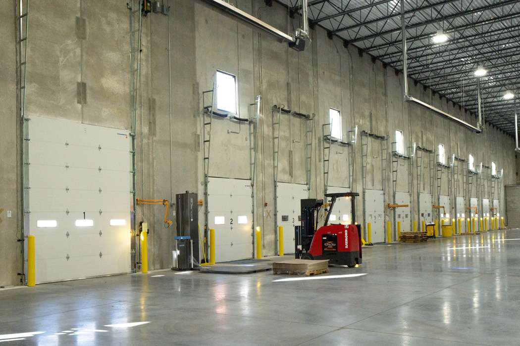 An industrial warehouse with multiple loading docks and a forklift.
