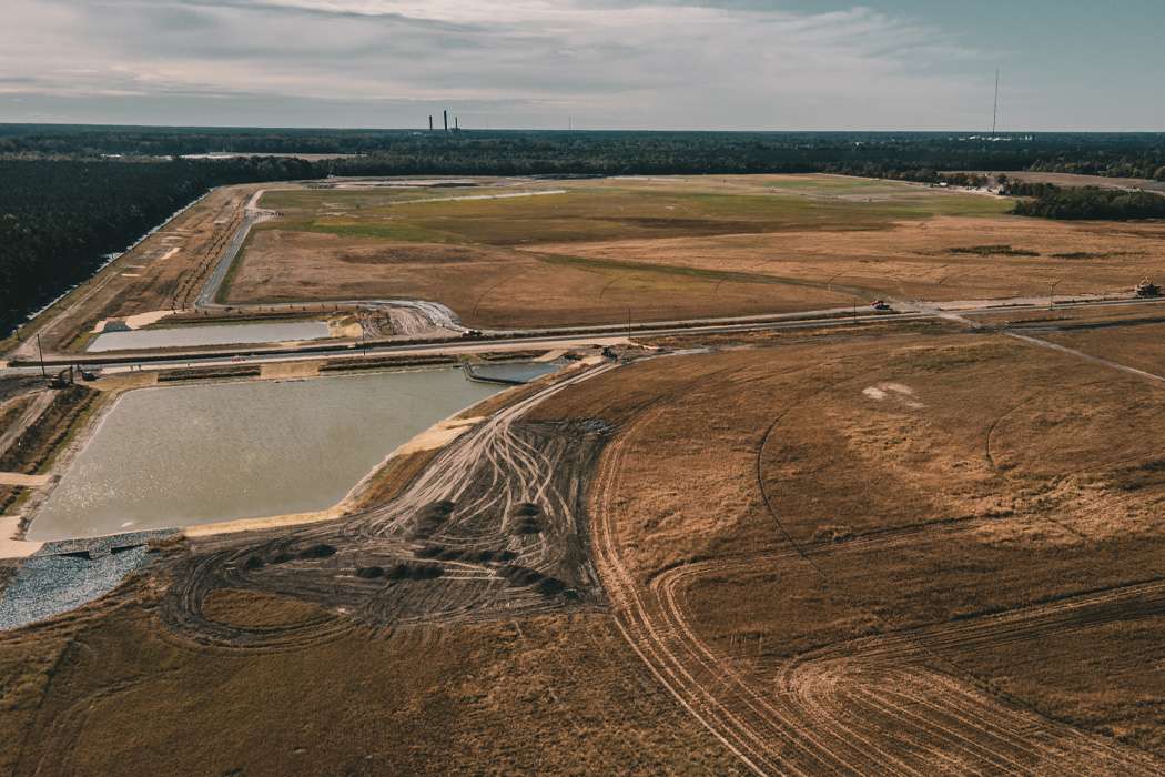 An aerial view reveals a sprawling landscape with water reservoirs and patches of brown fields under a cloudy sky.