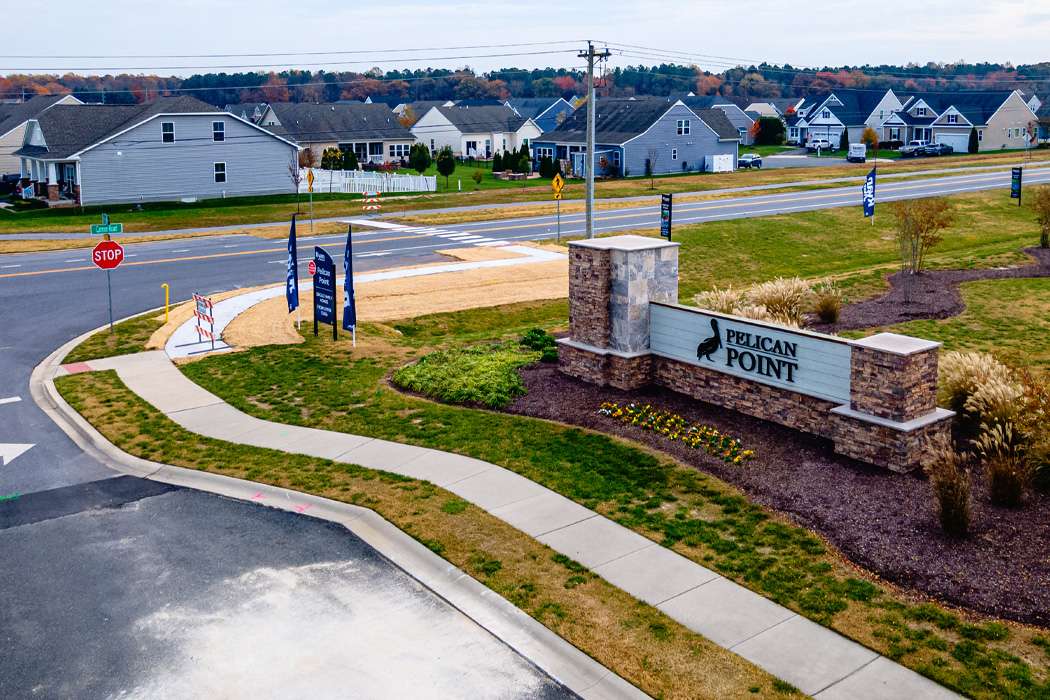A street corner features a "Pelican Point" sign and a stop sign, with houses in the background.