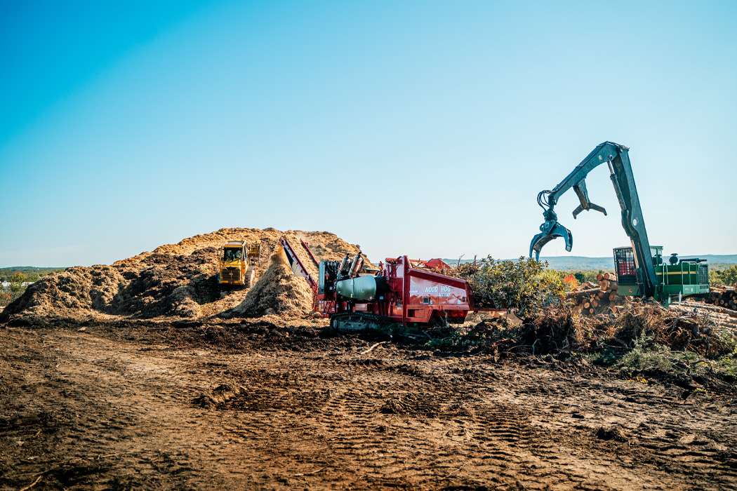 A red "Wood Hog 6400XT" machine grinds wood into mulch.