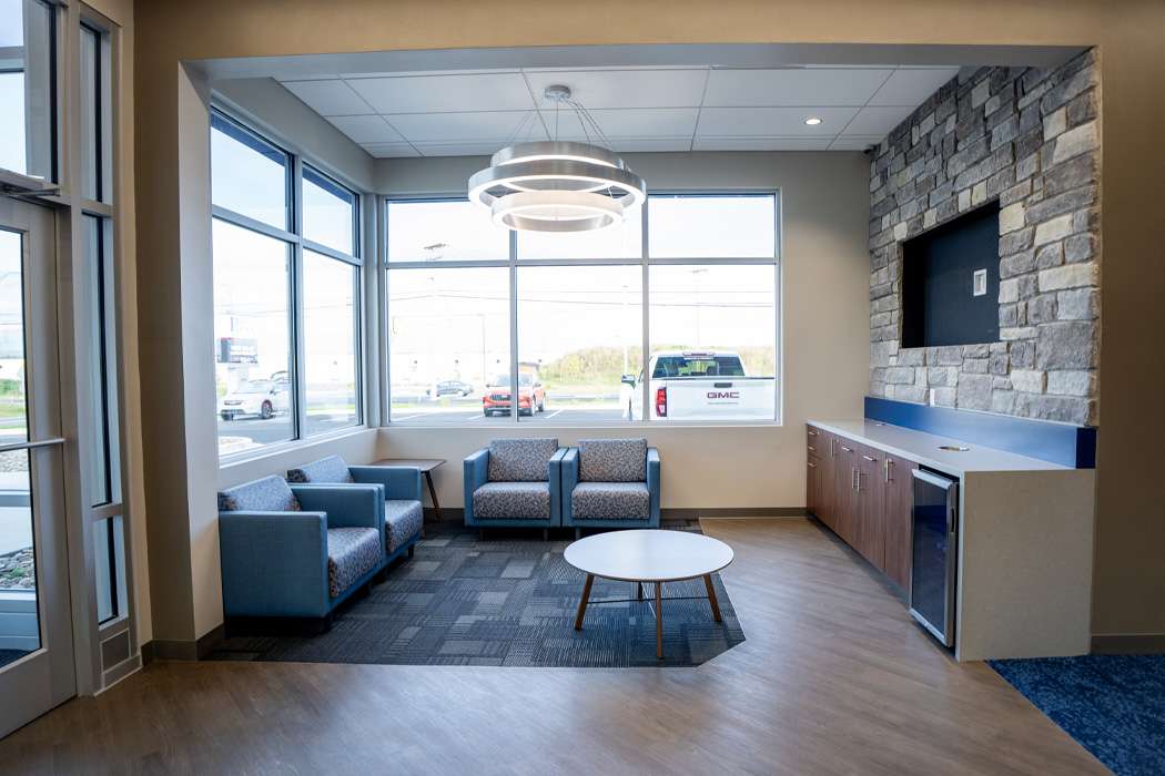 Lobby area with blue seating, a circular coffee table, and large windows.