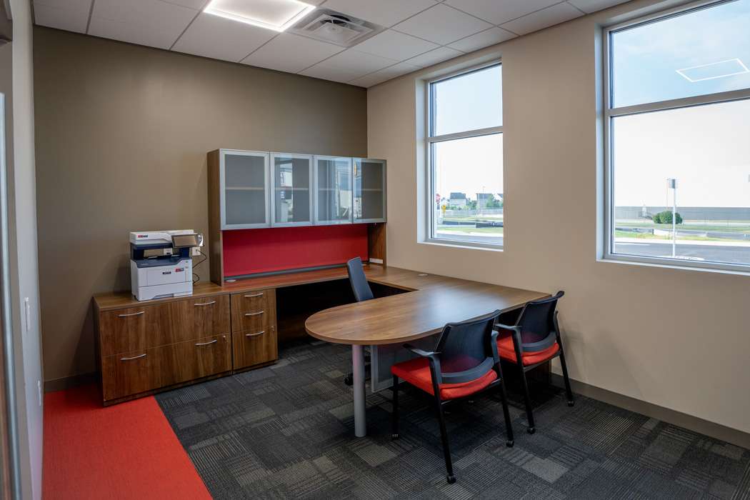 Office space with wood desk, cabinets, and red chairs.